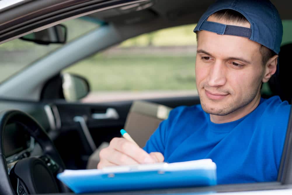 hombre escribiendo en una tableta dentro de un auto estacionado