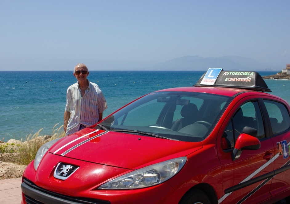 profesor al lado del coche de la autoescuela